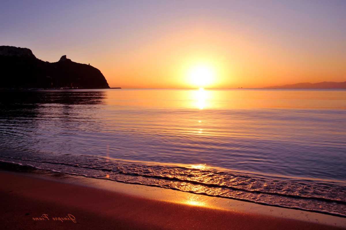 Un suggestivo tramonto sul Poetto di Cagliari, con i fenicotteri in lontananza
