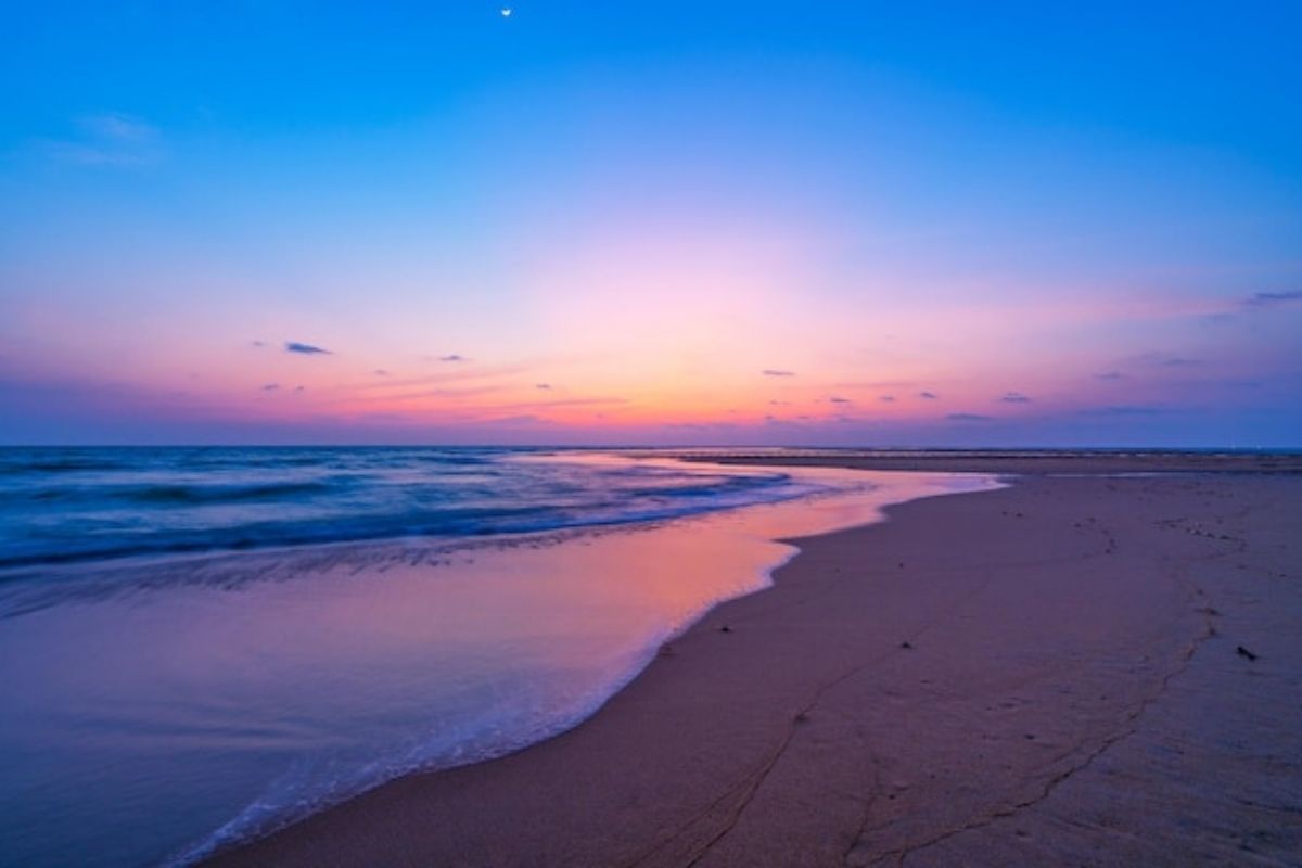 Spiaggia di Chia al tramonto, con le onde del mare e il cielo colorato
